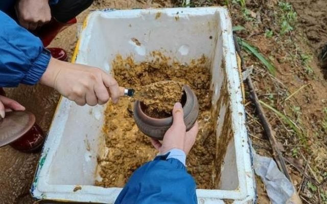 Families of passengers use clay pots to bring mud from the scene home